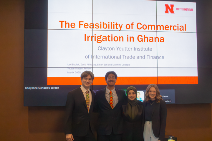 Four students standing in front of projector screen, their project title, "The feasibility of Commercial Irrigation in Ghana." From left to right, Matthew Gillespie, Ethan Zen, Zanib Al Razaq, and Lexi Bodlak